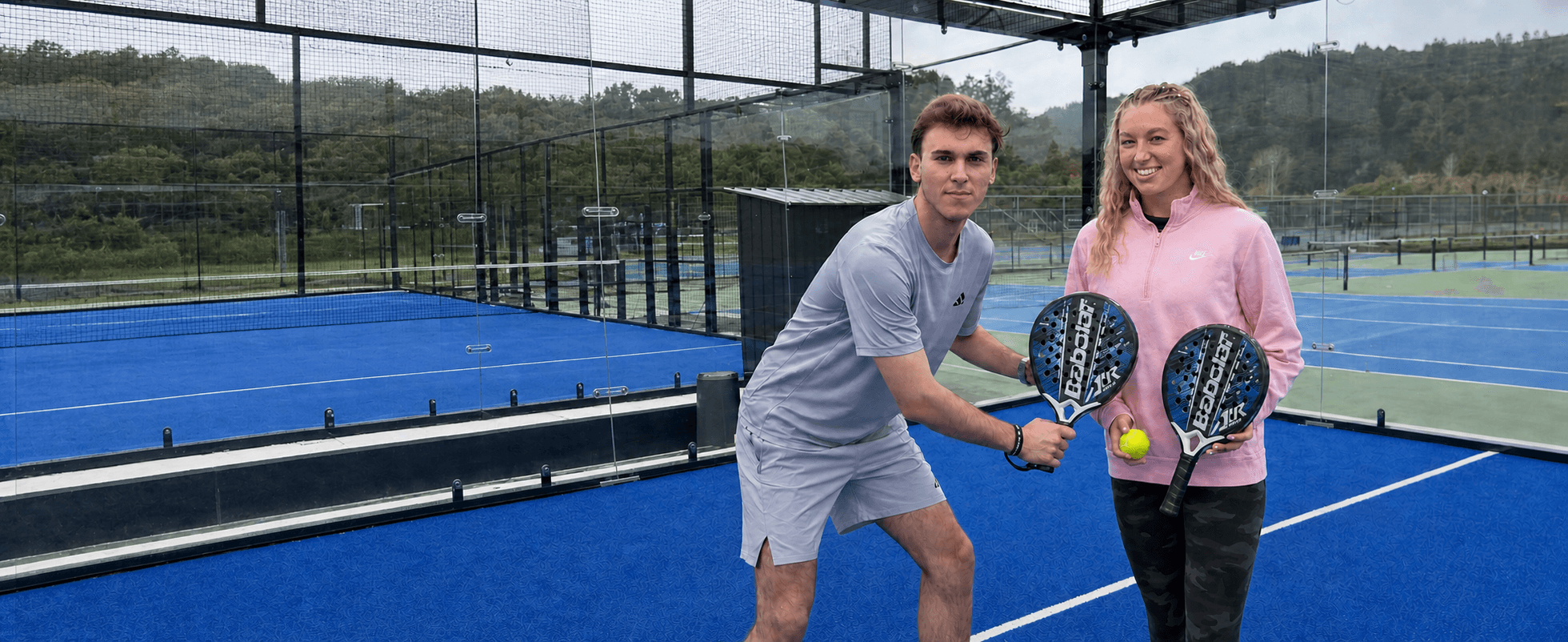 Maci and Samuel holding padel rackets and a ball